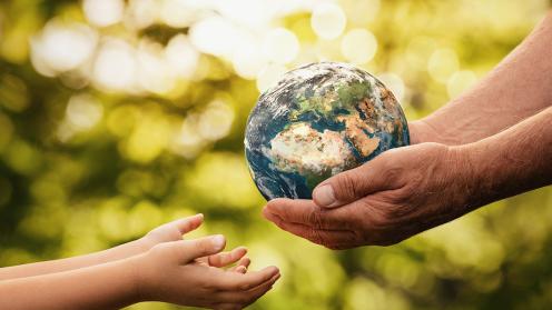 Senior hands giving small planet earth to a child