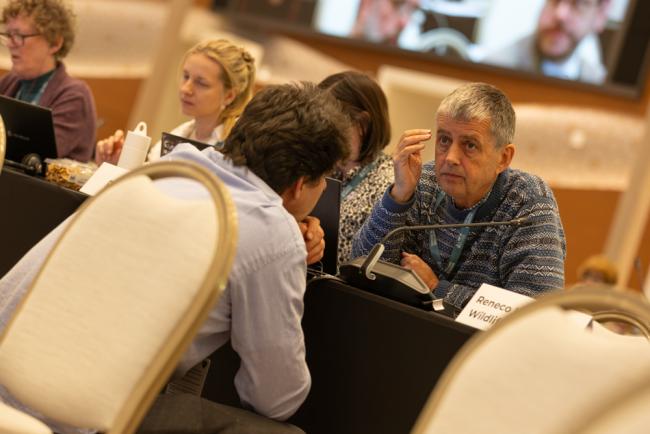 Delegates consult informally as the contentious issue of deep-sea mining is discussed in plenary