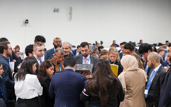 Delegates forming a huddle during informal negotiations on the work programme under the framework for non-market approaches referred to in Article 6.8 of the Paris Agreement